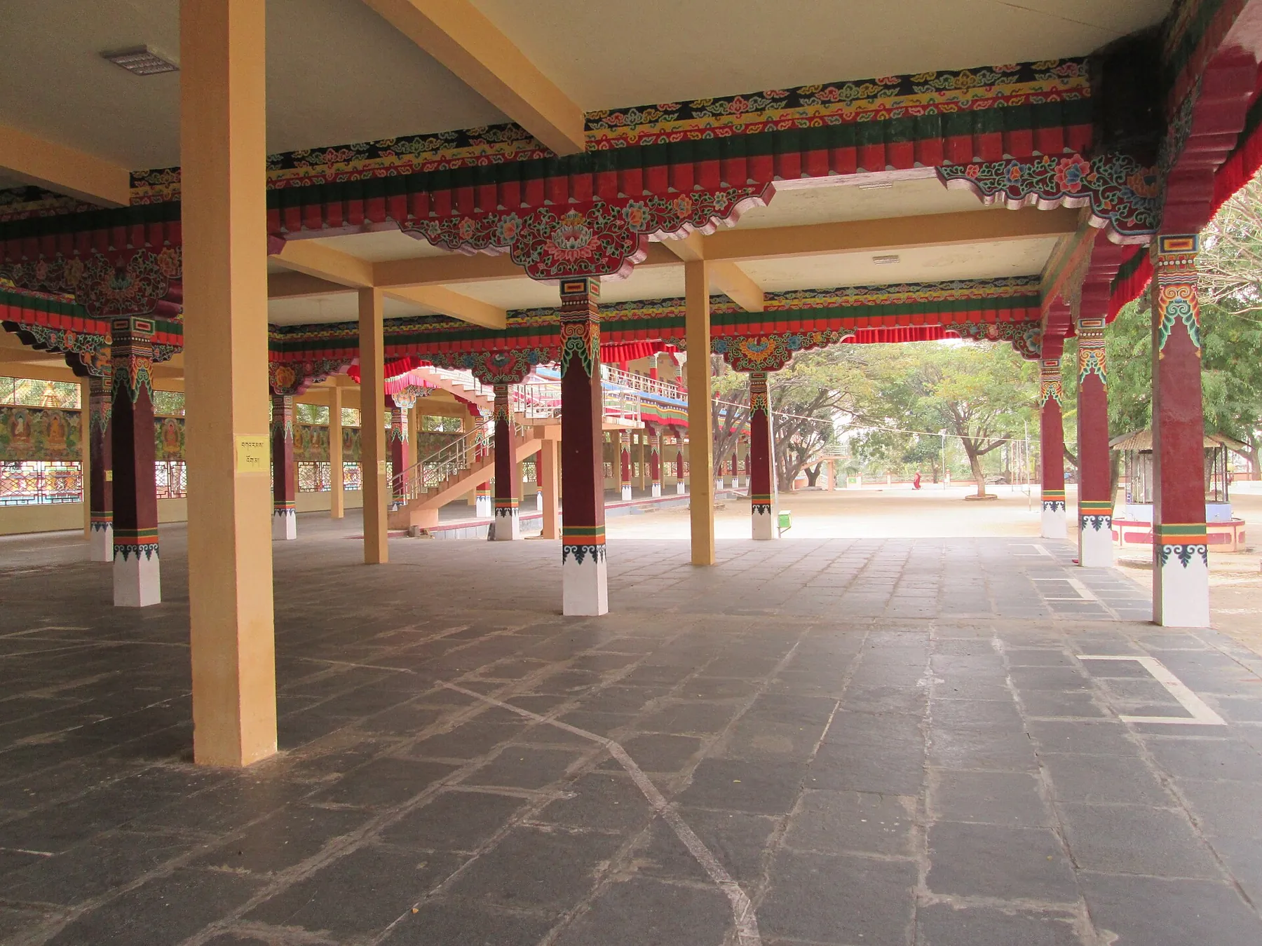 Painted pillars and carved eaves of the covered debate hall at Sera Jey
