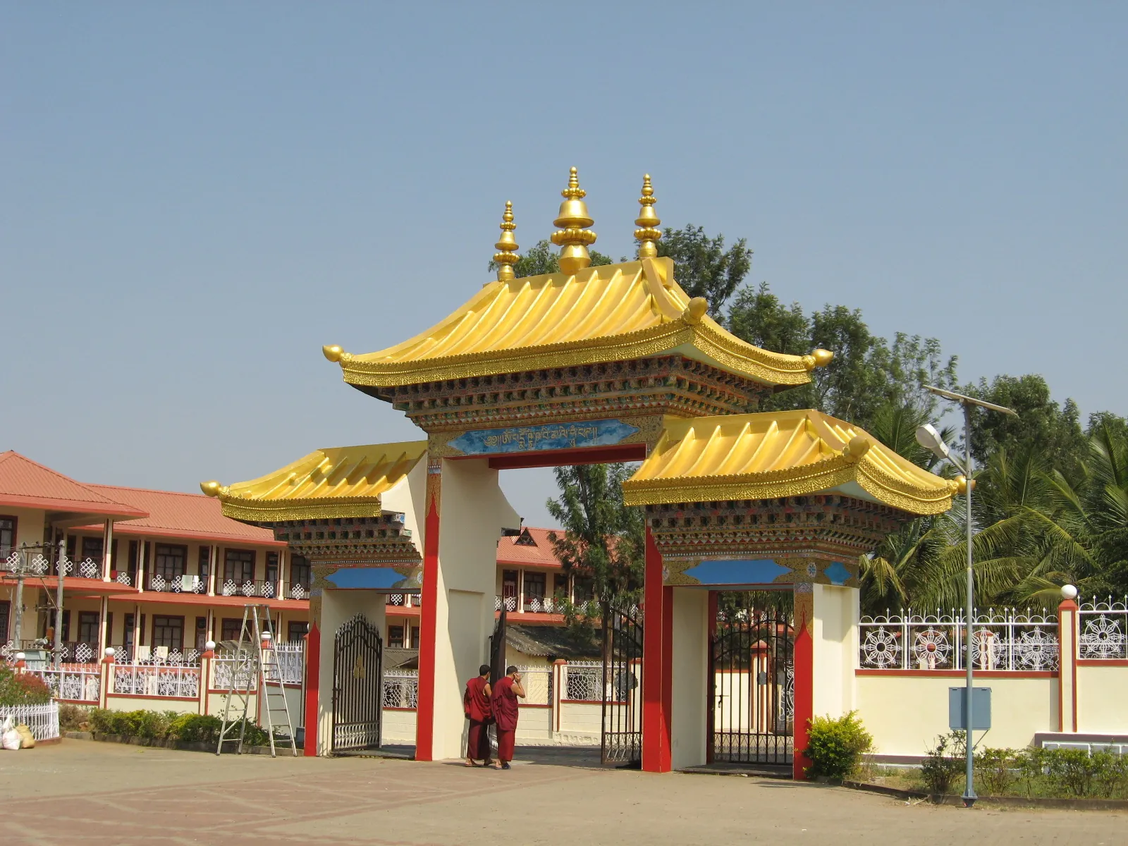 The triple-roofed ceremonial gate at Sera, Bylakuppe, with two monks passing through